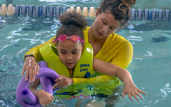 A swim instructor helping a participant stay afloat.