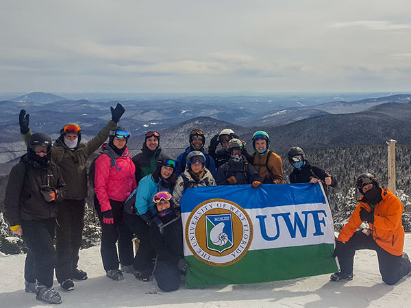 Spring Break Ski Trip Group photo; the students are holding up the UWF flag 