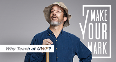 Dr John Worth in a floppy hat and dark blue shirt poses against a light gray background saying 