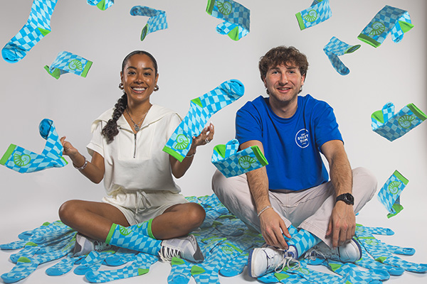 Two UWF students sitting with UWF Day of Giving socks 