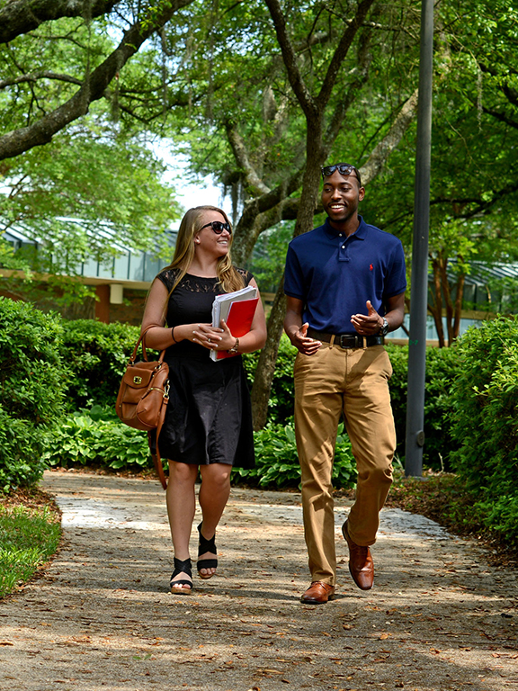 Two students conversing while walking through campus