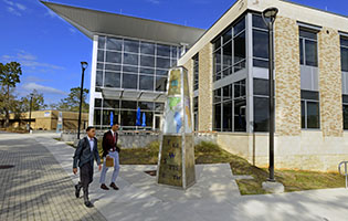 Two students in professional attire walking by Building 76A on the UWF Pensacola campus.