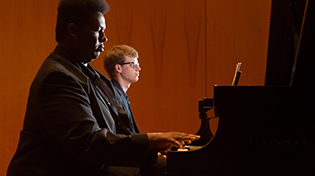 Two students playing a duet on Steinway pianos