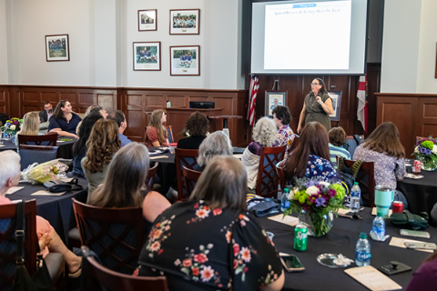 Dr. Blalock speaking in front of a room of people at round tables