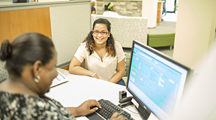 Student receiving assistance at Argo Central from an Argo Central employee using a computer.