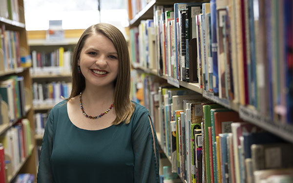 A student smiles while standing in the library.