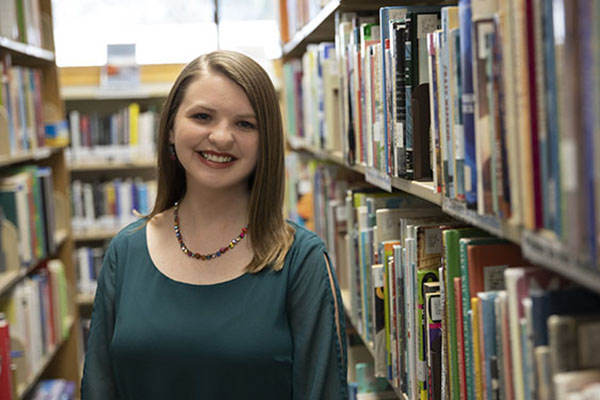 A student smiles while standing in the library.