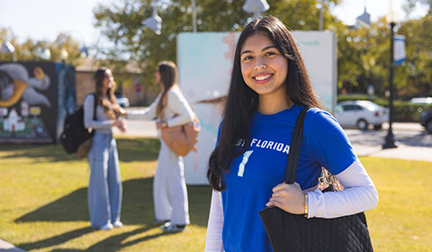 A UWF student smiles while wearing a backpack in downtown Pensacola.