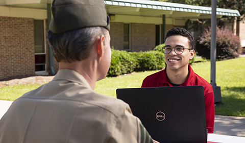 Two people chat over a laptop outside of the UWF MVRC.