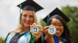 two students holding UWF medallions