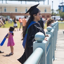 A Graduate student standing at a fence