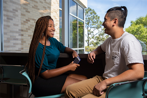 two students talking in chairs