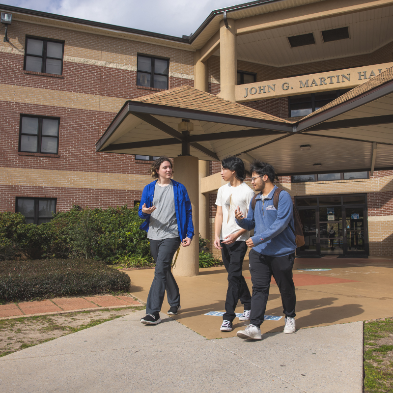 3 students walking outside Martin  Hall talking with each other