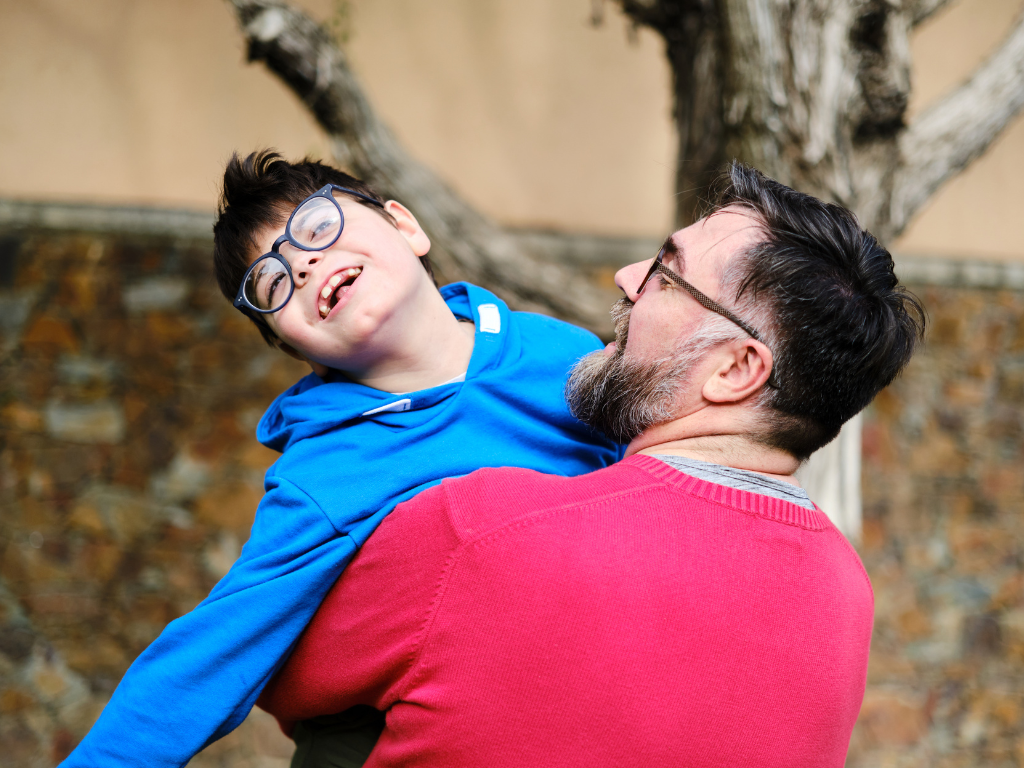 A man holds a child up in the air joyfully