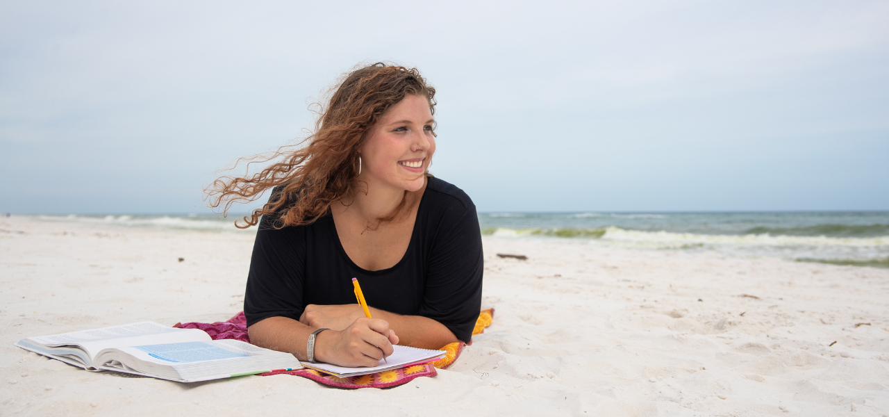 A student studies while on the beach