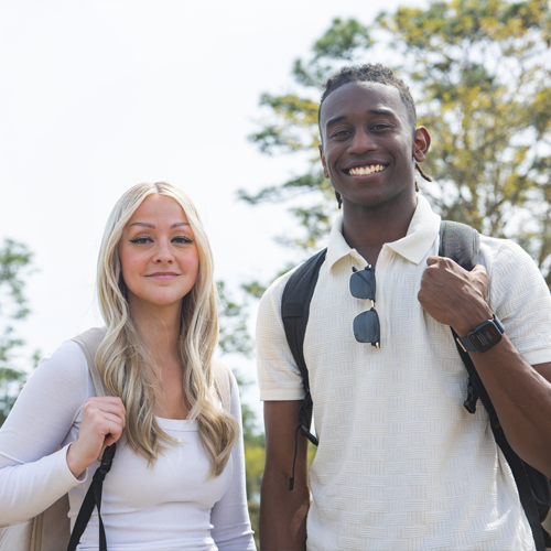 Two students in white shirts standing and smiling in front of camera