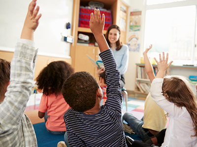 Teacher in class with students hands raised