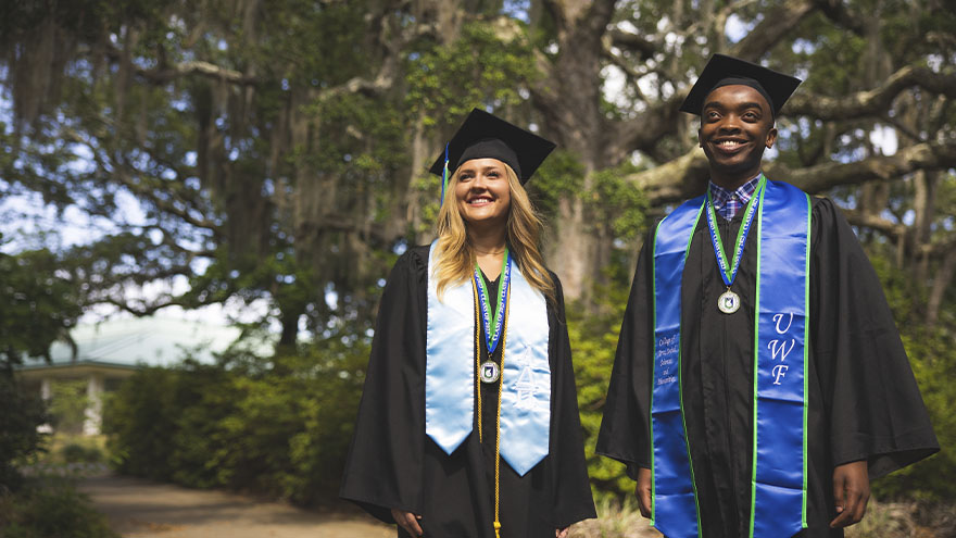 Two students standing in cap and gown
