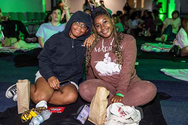 students sitting on a blanket, wearing hoodies and eating popcorn