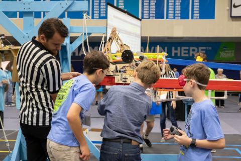 Three students working on a robot for the Robotics competition