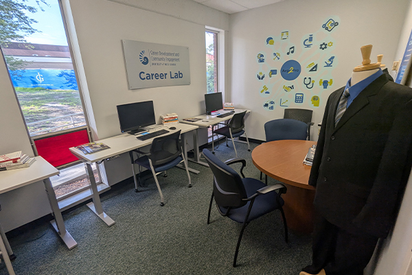 two empty work stations with computer and table with chairs
