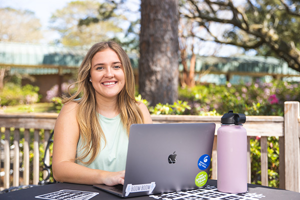 A student using a laptop while sitting at an outdoor table.