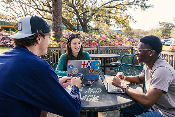 students with laptops at outdoor table