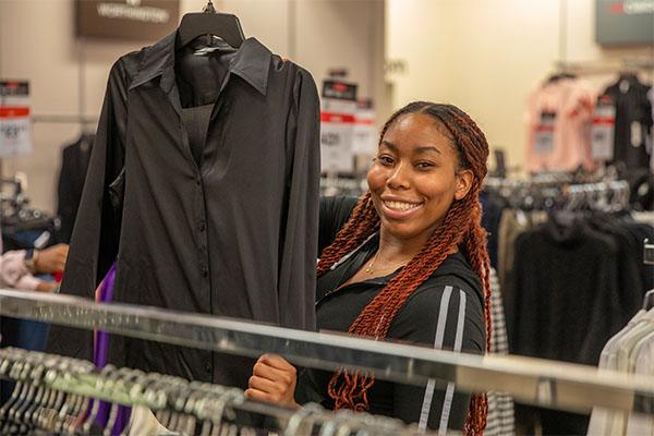 Student holding suit items