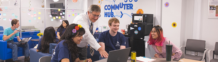 Staff member working with three students in the Commuter Hub