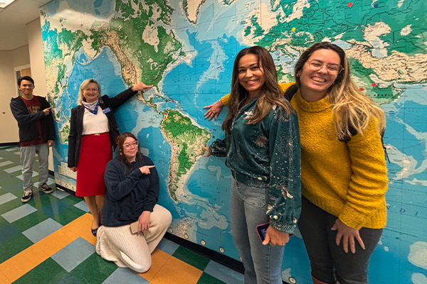 Students posing in front of global mural
