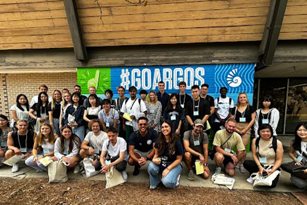 Group of students posing in front of mural