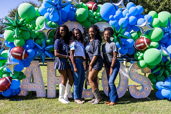 a group standing in front of Go Argos signage at tailgate