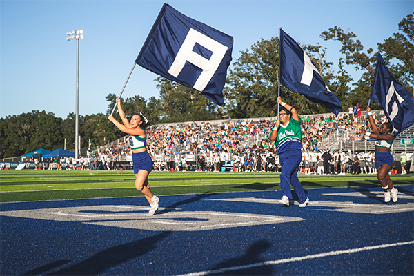 Cheerleaders running across field at Homecoming Game