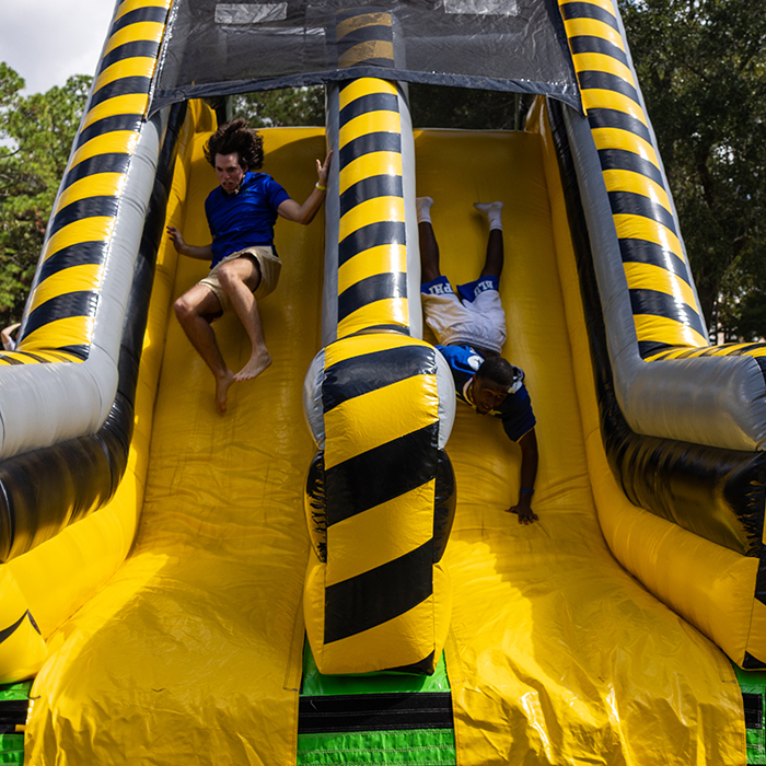 students sliding down blow up slide for