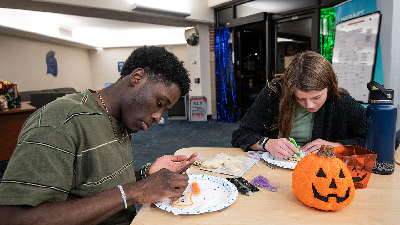 Two people working on crafts and decorations in a common room