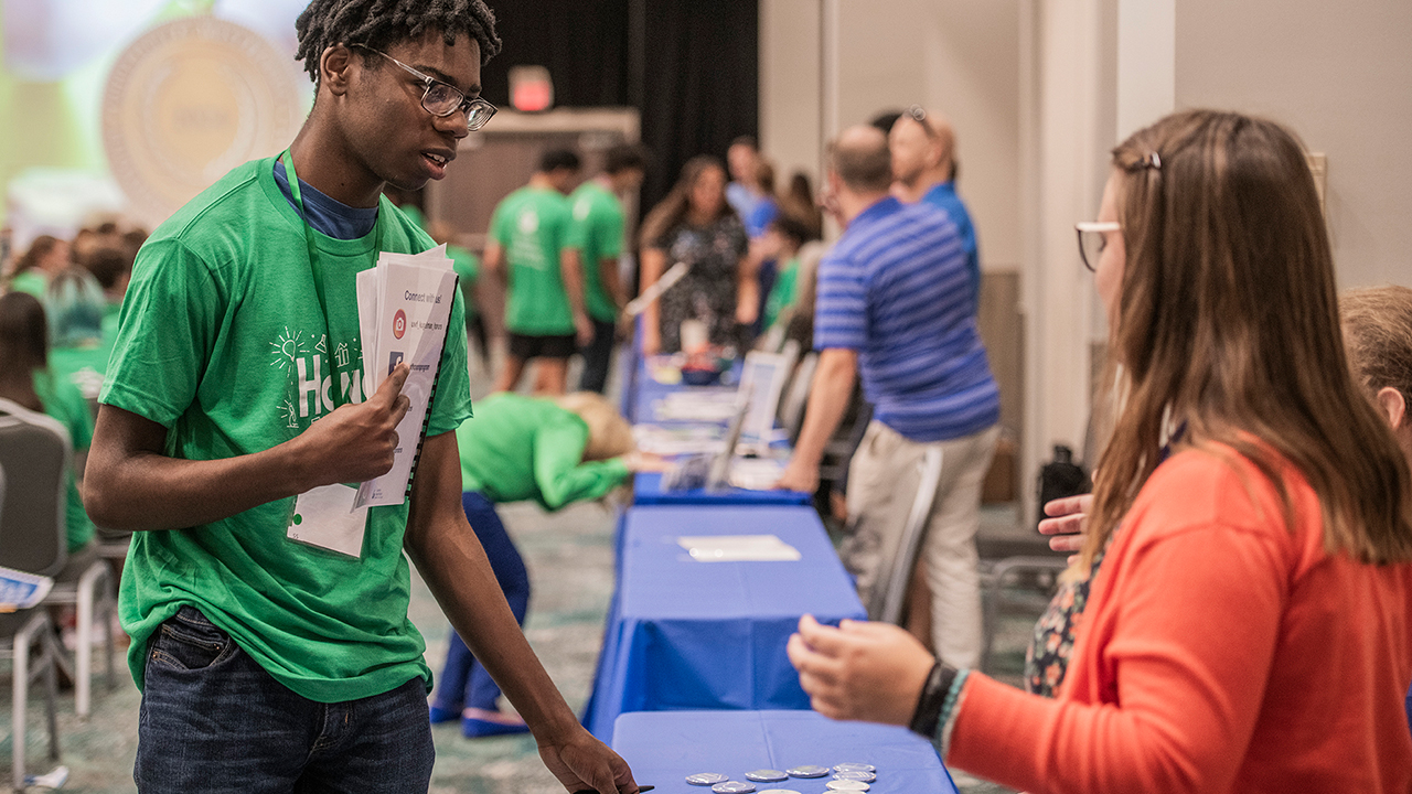 People conversing across a table set up in a row in the Commons Auditorium