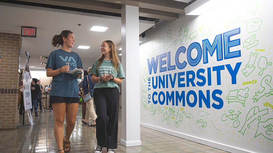 Two students walking down the Commons consource hallway.