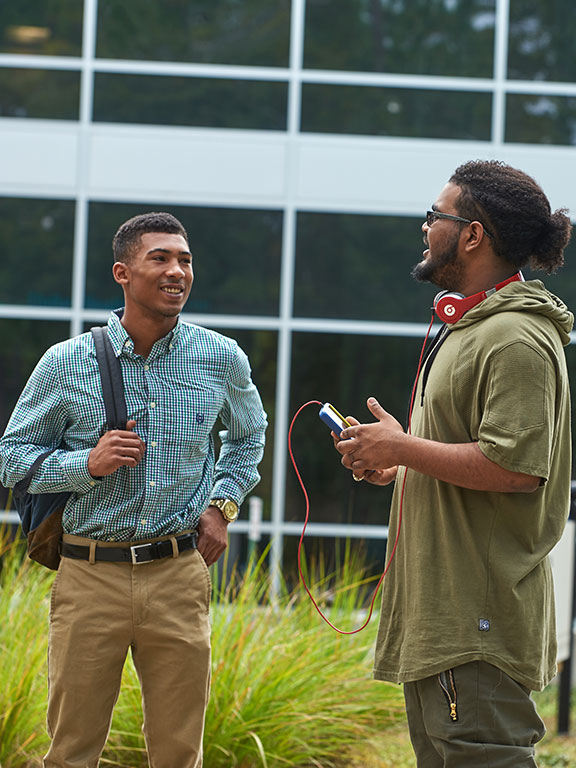 two students conversing outside of the college of business building