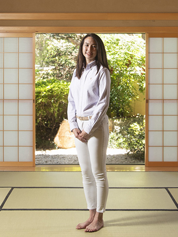 A person smiles while standing barefoot in the tea room at the UWF Japan House.