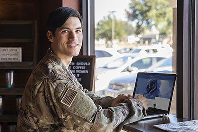 A UWF student and military veteran visits the UWF site from a laptop.