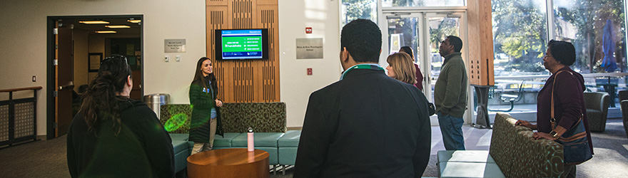 A student tour guide leads a group of guests in Building 76A.