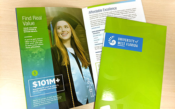 A UWF Freshman Admissions recruitment booklet sits open to financial aid information on a desk.