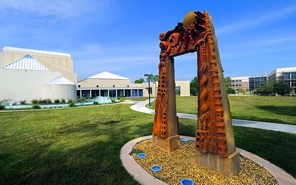 A sculptured arch stands in front of the UWF Center for Fine and Performing Arts.