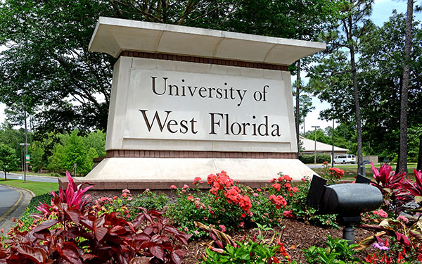 The main entrance sign to UWF's Pensacola campus is surrounded by flowers.