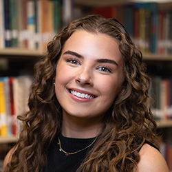 Alexis Walders indoor headshot in business attire against a shelf of books in a library.