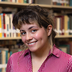 Laila Chavarrie Service indoor headshot in business attire against a shelf of books in a library.