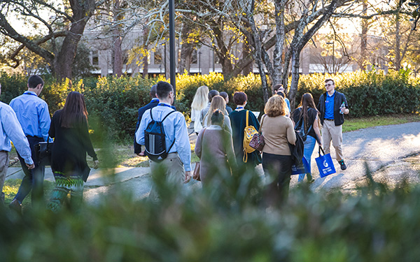 A tour guide walks a group across campus.