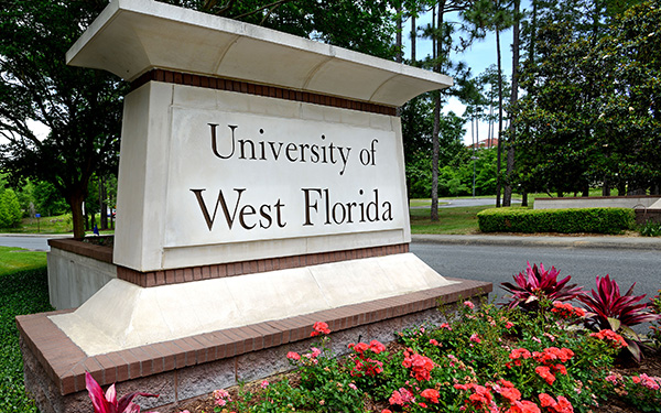 The UWF main entrance sign is surrounded by flowers.