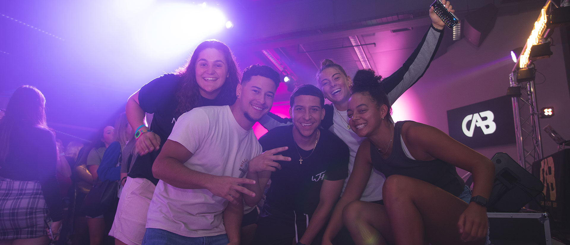 Four students partying at a Campus Activity Board event with dramatic purple lights