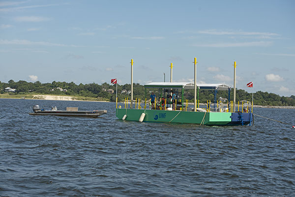 A UWF dive platform with a small boat in a water bay.